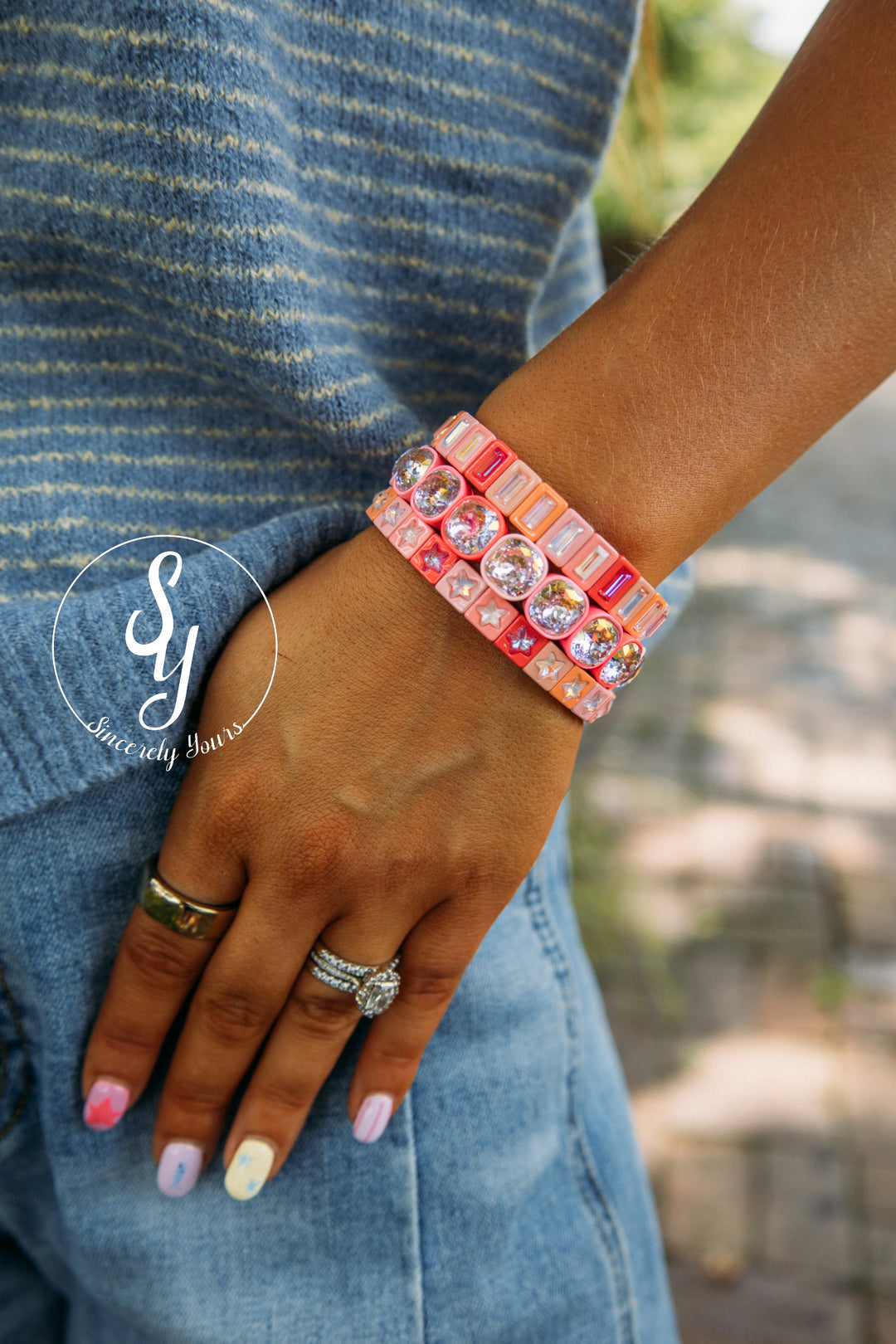 Close-up of a hand wearing a colorful bracelet with a blurred outdoor background