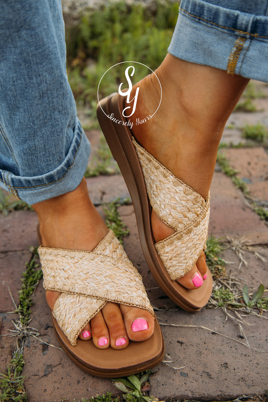 Close-up of feet wearing woven sandals on a stone surface.