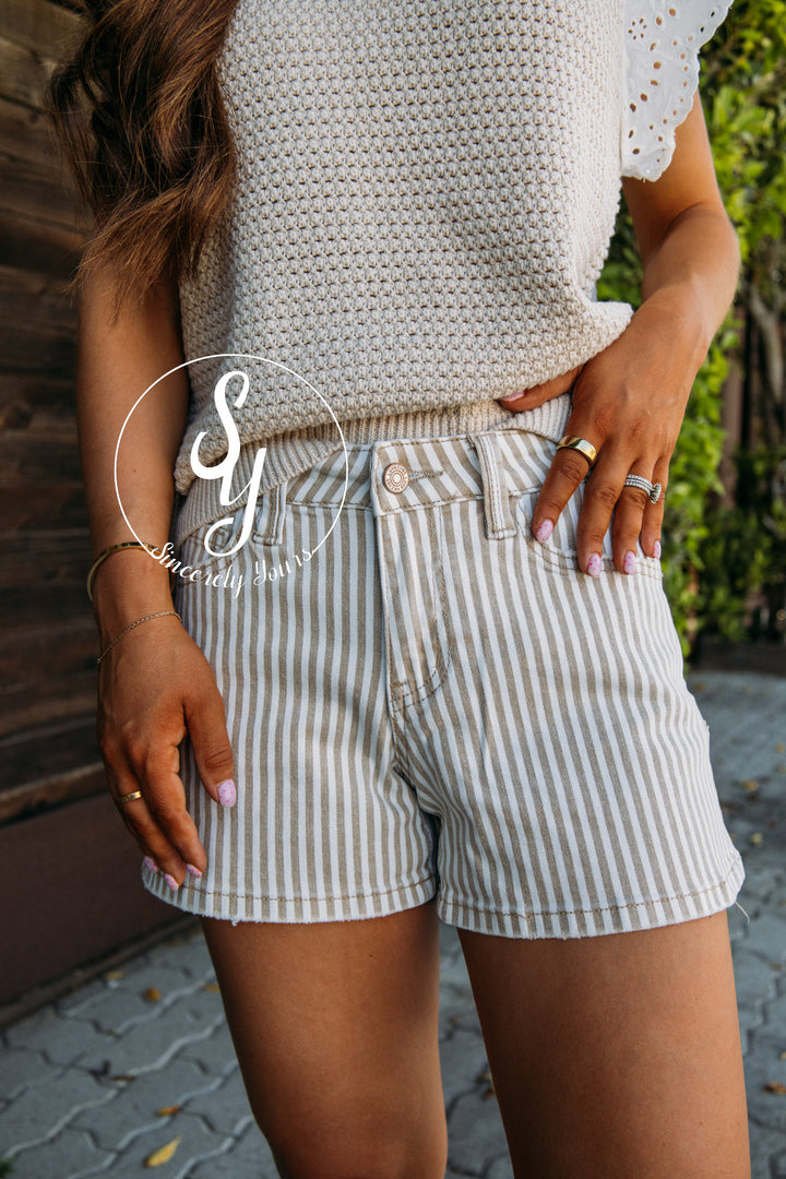 Person wearing a beige crochet top and striped shorts outdoors