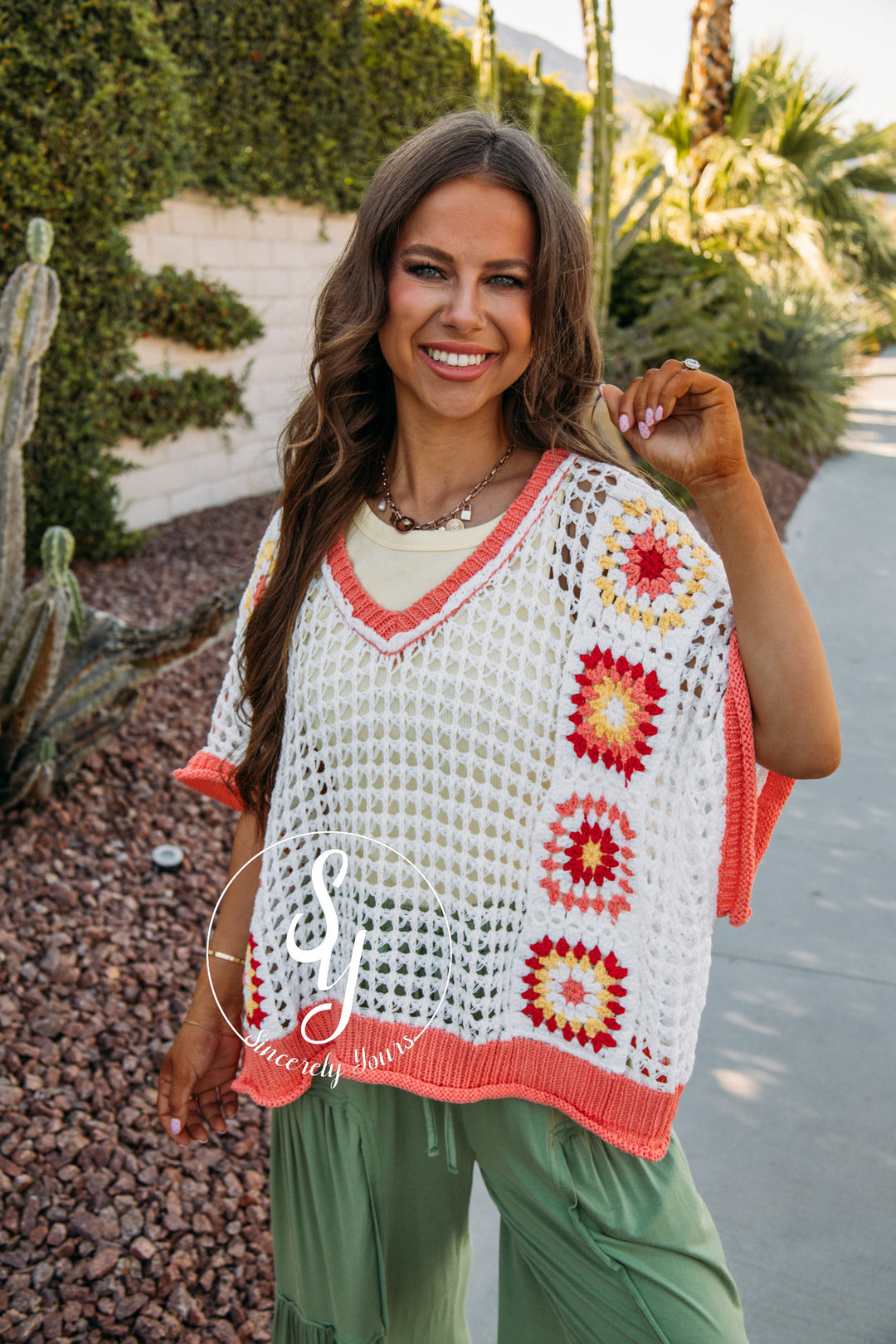 Woman wearing a colorful crochet top with a desert landscape in the background