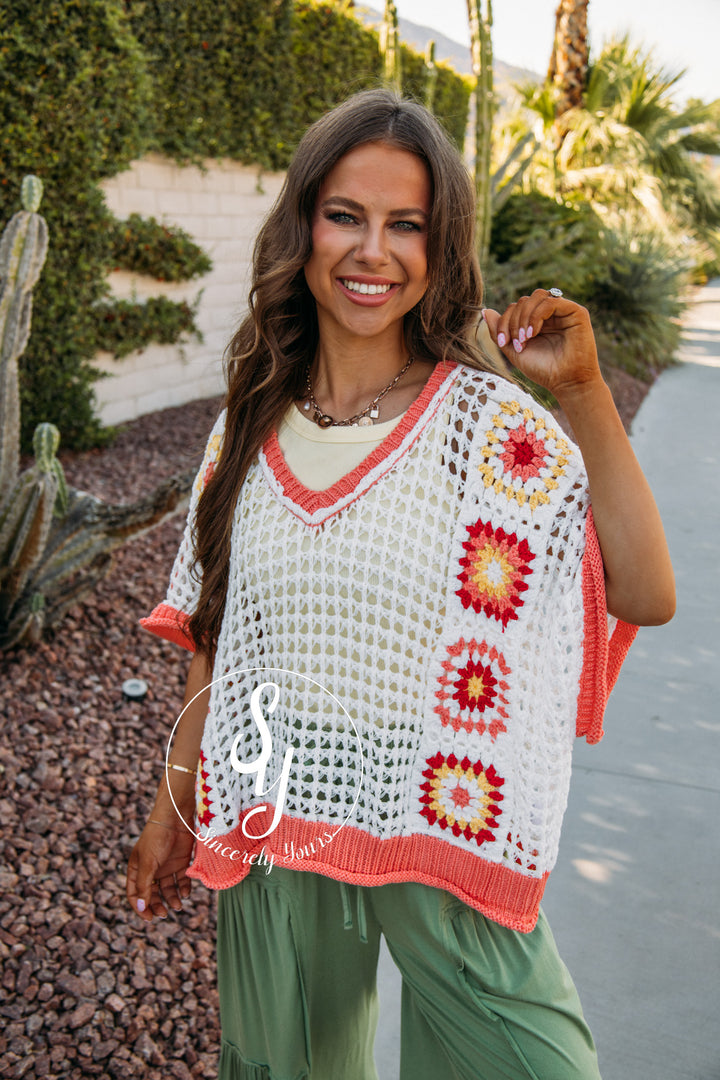 Woman wearing a colorful crochet top with a desert landscape in the background