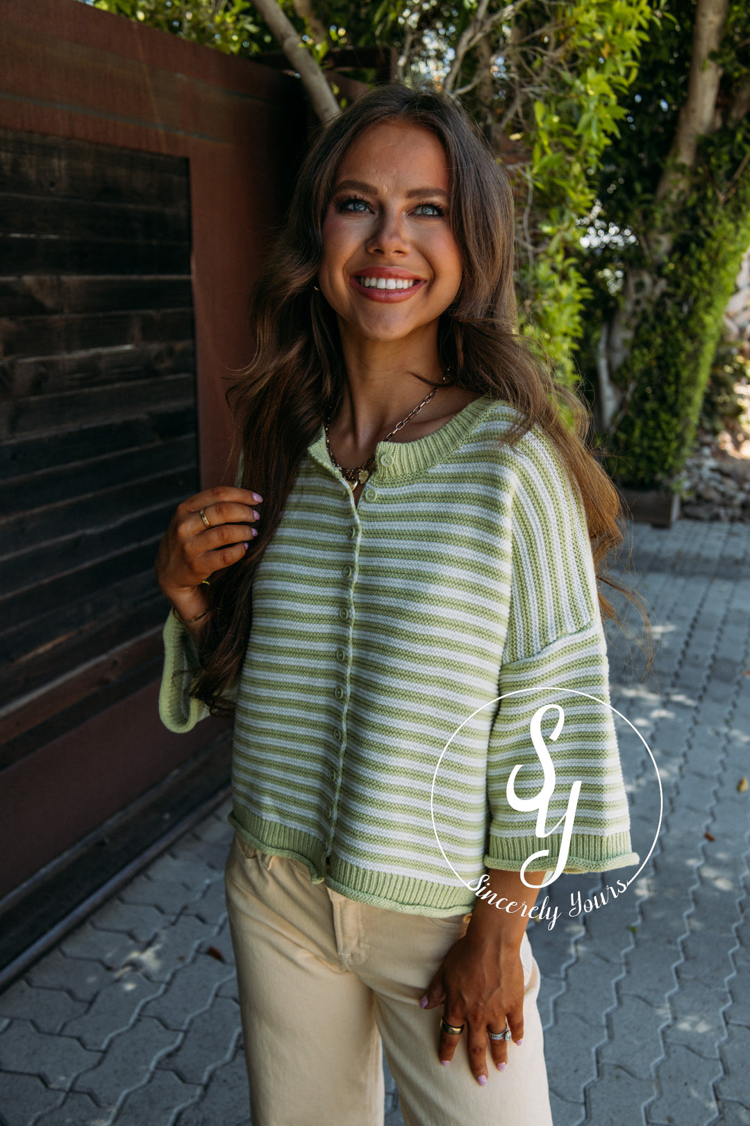 Woman wearing a green and white striped sweater standing outdoors.