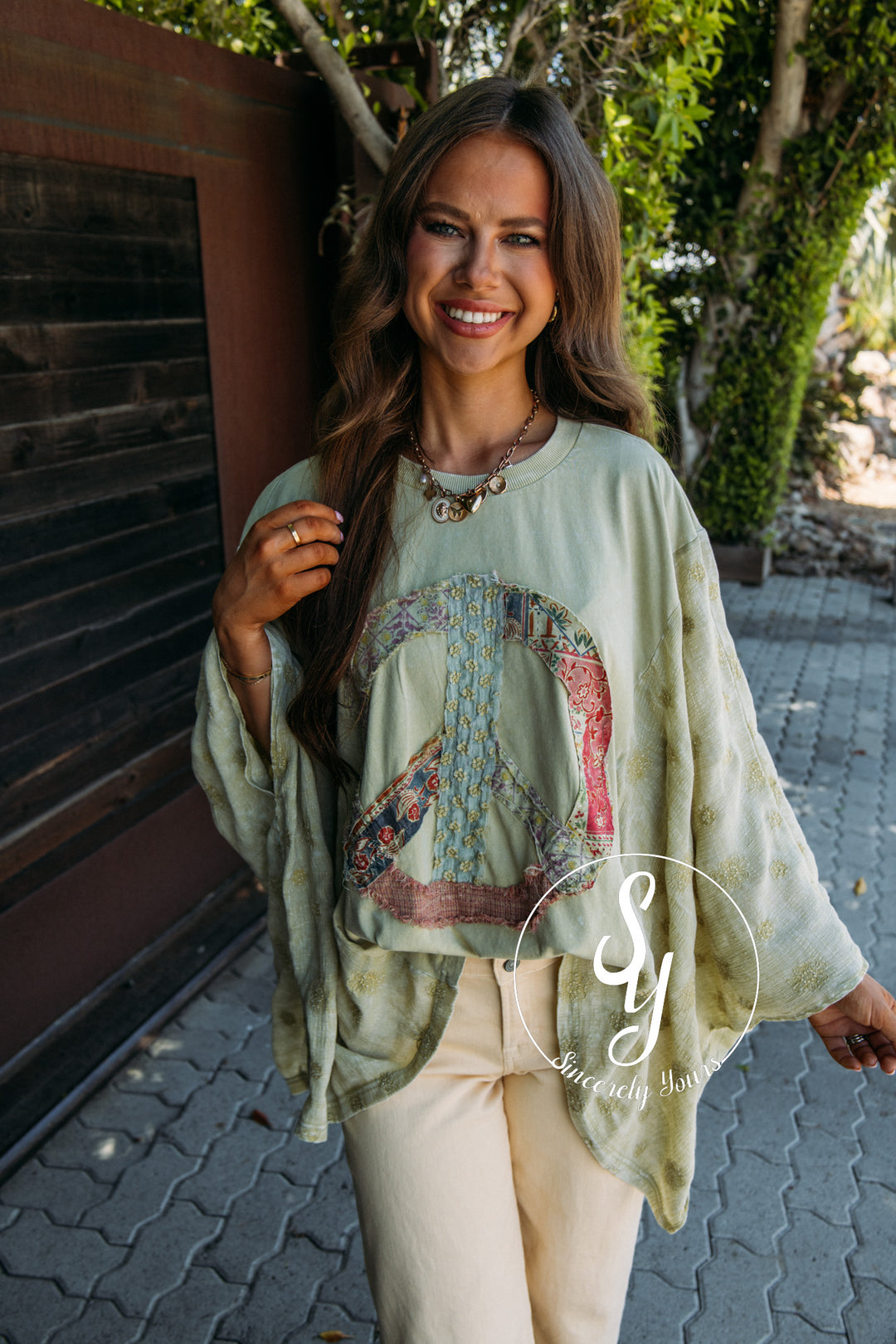 Woman wearing a light green oversized shirt with a graphic design, standing outdoors.