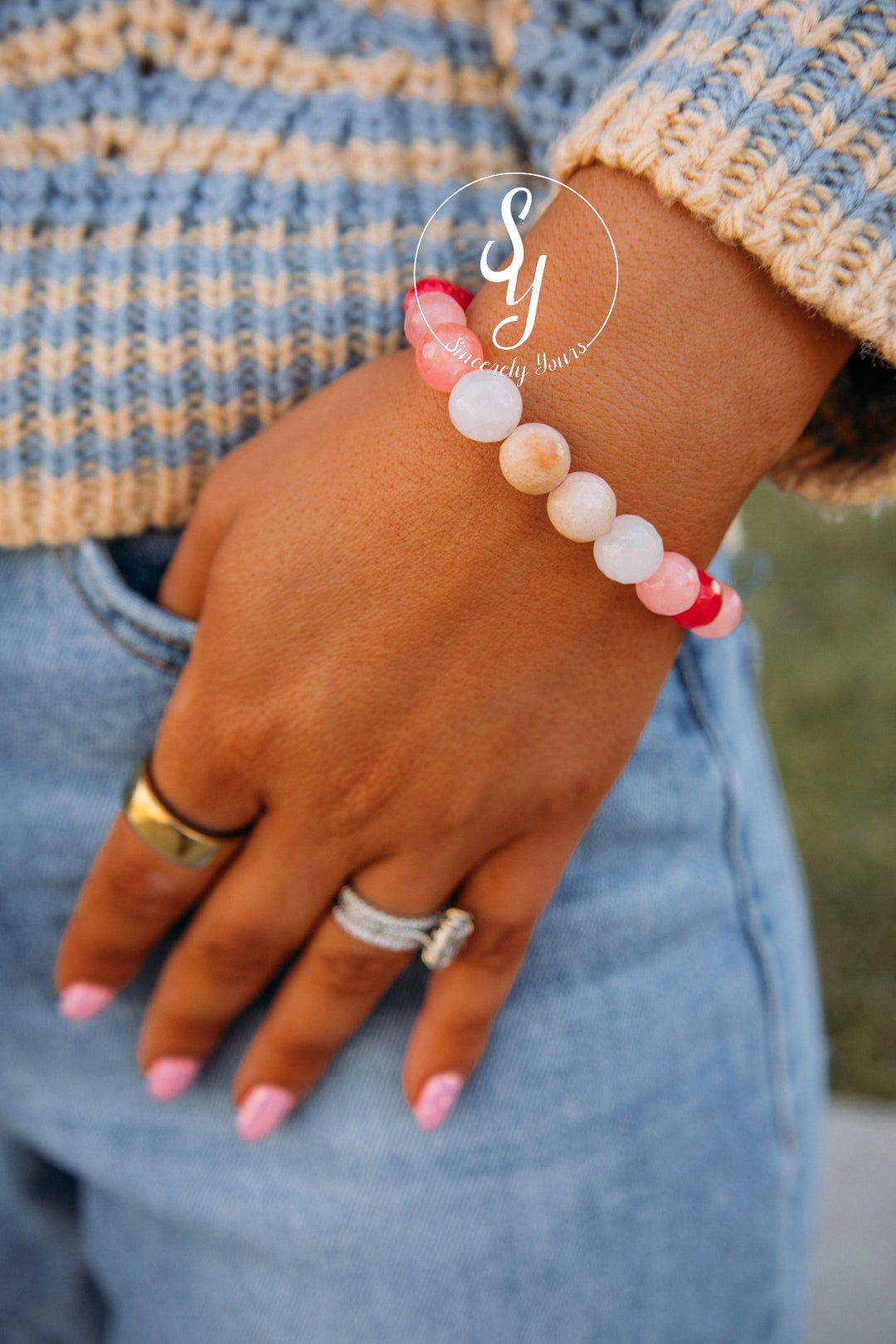 Hand wearing a beaded bracelet with a blurred background