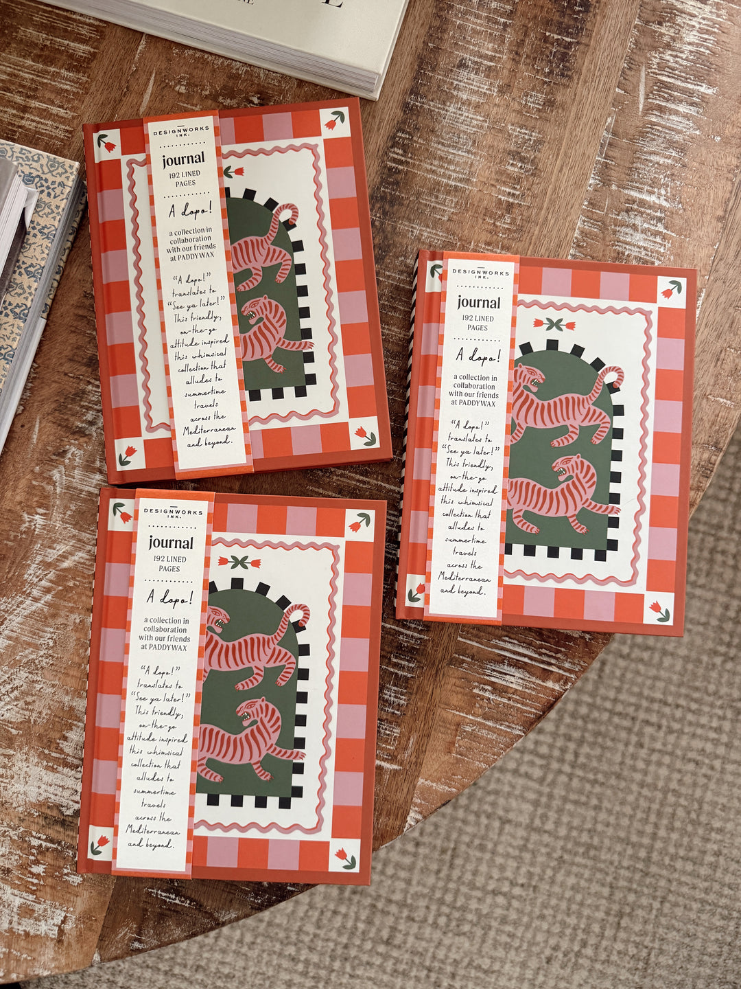 Three small journals with tiger illustrations on a wooden surface